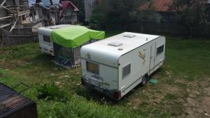 two rvs parked in a yard with a tent at Camping Aviator Busteni, Parcare rulota termen lung (6-12 luni). in Buşteni