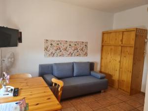 a living room with a blue couch and a wooden table at Ferienwohnungen Ödenburgerhof in Mörbisch am See