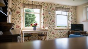 a living room with a table and two windows at Winsbury Cottage in West Hauxwell