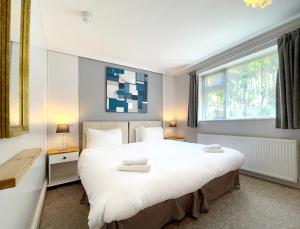 a bedroom with a large white bed and a window at Dukes Folly Hotel in Southport