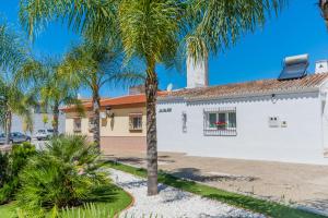 a white building with palm trees in front of it at Cubo's Casa de Rebollo in Cártama