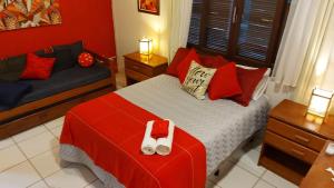 a bedroom with a bed with red pillows and a red wall at Pousada VistaCalma in Praia do Rosa