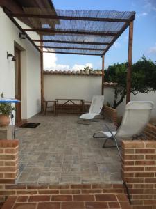 a patio with two white chairs and a table at Agriturismo Le Terre Di Zoe' in Limbadi