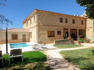 Un edificio con piscina enfrente. en Casa Rural Galatea especial Grupos, en Ossa de Montiel