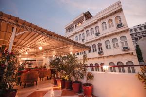 een patio met stoelen en planten voor een gebouw bij Hotel Devraj Niwas on Lake Pichola in Udaipur