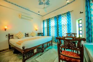 een slaapkamer met een groot bed en blauwe gordijnen bij Hotel Devraj Niwas on Lake Pichola in Udaipur +37 foto's