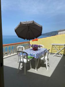 una mesa y sillas con una sombrilla en el balcón en A picco sul mare, en Marina