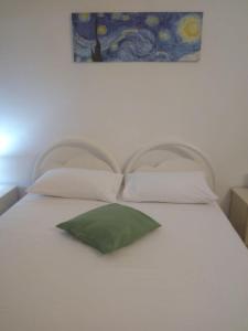a white bed with a green pillow on it at Casa Orchidea in Siracusa