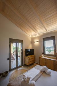 1 dormitorio con 1 cama, TV y ventana en Théa boutique villas sivota III, en Sivota