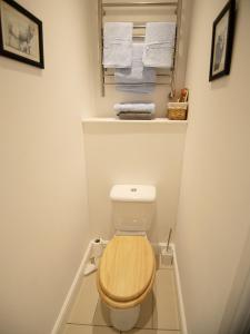a bathroom with a toilet with a wooden seat and towels at Walwyn Court Barns in Ledbury +40 photos