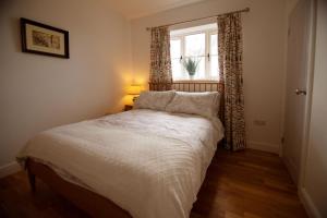 sypialnia z białym łóżkiem i oknem w obiekcie Walwyn Court Barns w mieście Ledbury
