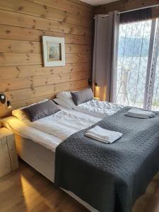 Cama grande en habitación con pared de madera en Småstranda Fjord Lodge en Åheim