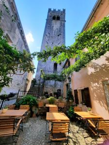 een patio met tafels en stoelen en een toren bij Bed & Breakfast Antico in Motovun
