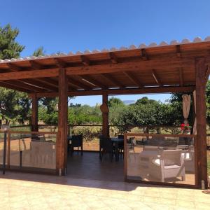 pérgola de madera con mesa y sillas en el patio en B&B SiciliAntica, en Rilievo