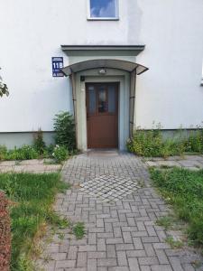 a building with a brown door and a brick walkway at Apartament komfortowy Levino in Lębork