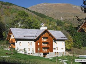 una casa in un campo con una montagna sullo sfondo di Les Chalets du Galibier II a Valloire