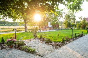 a garden with a bench and flowers in a park at Natura Apartman Tiszafüred in Tiszafüred