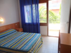 1 dormitorio con 1 cama y puerta corredera de cristal en Hotel Canaima en Tossa de Mar