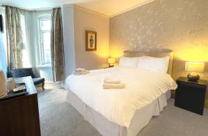 a bedroom with a large white bed with towels on it at Dukes Folly Hotel in Southport