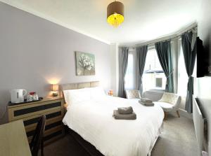 a bedroom with a large white bed and a chair at Dukes Folly Hotel in Southport