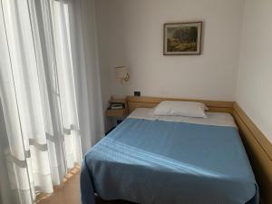 a small bedroom with a blue bed and windows at Hotel Angiolino in Chianciano Terme