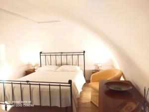 een witte slaapkamer met een bed en een stoel bij La Perla in Francavilla Fontana