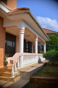 ein Haus mit einer Veranda mit einem weißen Geländer in der Unterkunft Nile Estates Villa Kiwatule in Kampala