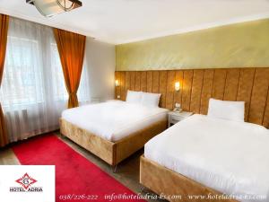 Habitación de hotel con 2 camas y alfombra roja en Hotel Adria, en Pristina