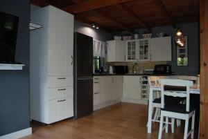 a kitchen with white cabinets and a black refrigerator at Dom na Kaszubach - Lewinko in Lewinko