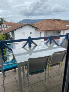 d'une table et de chaises blanches sur un balcon. dans l'établissement LES HAUTS DE BIANTENIA AVEC WIFi, à Hendaye
