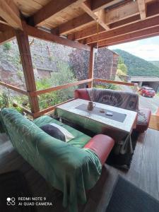 un patio avec un canapé et une table sur une terrasse dans l'établissement Maison de campagne tout confort, bol d'air frais, à Saint-Beauzély