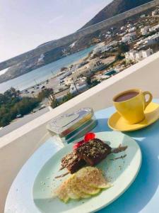 einen Teller mit einem Stück Kuchen und einer Tasse Kaffee in der Unterkunft Helios Pension in Chora, Ios