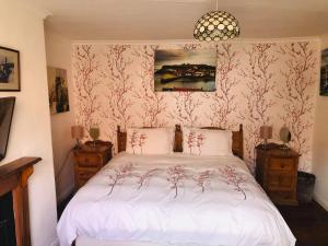 a bedroom with a bed with white sheets and floral wallpaper at Endeavour Cottage Whitby sleeps 6 in Whitby