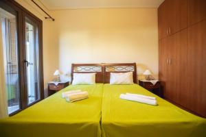 a yellow bed with two towels on top of it at VILLA KAROLINA Tsogkas in Syvota