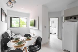 a white living room with a table and chairs at Quinta do Mar Flats Porto de Galinhas in Porto De Galinhas