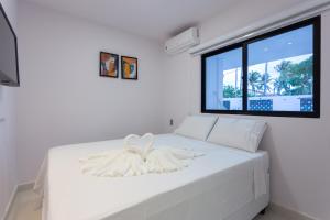 a white bed in a room with a large window at Quinta do Mar Flats Porto de Galinhas in Porto De Galinhas +50 photos