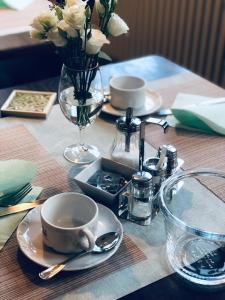 einen Tisch mit Teller und Tassen und eine Vase Blumen in der Unterkunft Hotel Altstadt Wöllbacher Tor in Wetzlar
