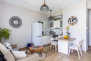 a kitchen and living room with white cabinets and a table at Artemis' Garden in Skopelos Town