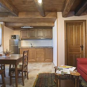 cocina con mesa y sofá rojo en Apartamento La Corrada, en Santa Eulalia de Oscos