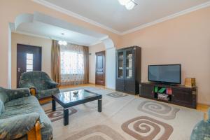 sala de estar con sofá y TV en Alvani Inn en Nizhniy Alvani