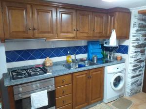 a kitchen with wooden cabinets and a sink and a washing machine at Cantinho Casal do Rei in Seia