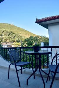 a table and chairs on a balcony with a hill at Tasos house in Anthoúsa