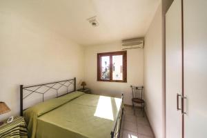 1 dormitorio con cama, ventana y silla en Giallomare en Marzamemi