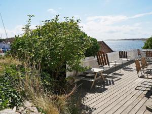 a wooden deck with chairs and a bush next to the water at 6 person holiday home in H LLEVIKSSTRAND in Hälleviksstrand