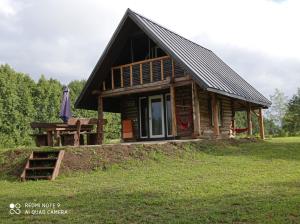 ein Blockhaus mit einem Tisch und einem Sonnenschirm in der Unterkunft KUNDZINIŠĶI in Leitāni