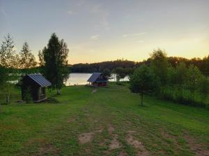 a cabin in a field next to a lake at KUNDZINIŠĶI in Leitāni