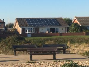 two park benches in front of a house with solar panels at Pagham Getaways in Pagham