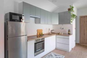 a kitchen with white cabinets and a stainless steel refrigerator at Stay Veszprèm, modern city center flat in Veszprém