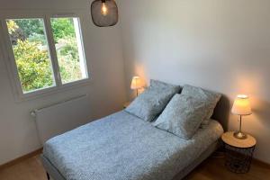 a bedroom with a bed with blue sheets and two lamps at Grande maison neuve idéale pour 6 personnes in Saint-Loubès