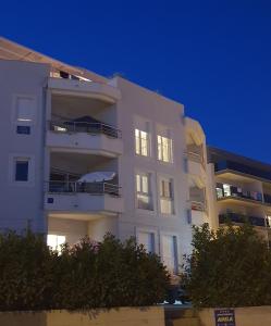 ein weißes Apartmenthaus mit nachts eingeschaltetem Licht in der Unterkunft Adela Apartments Žnjan Split in Split